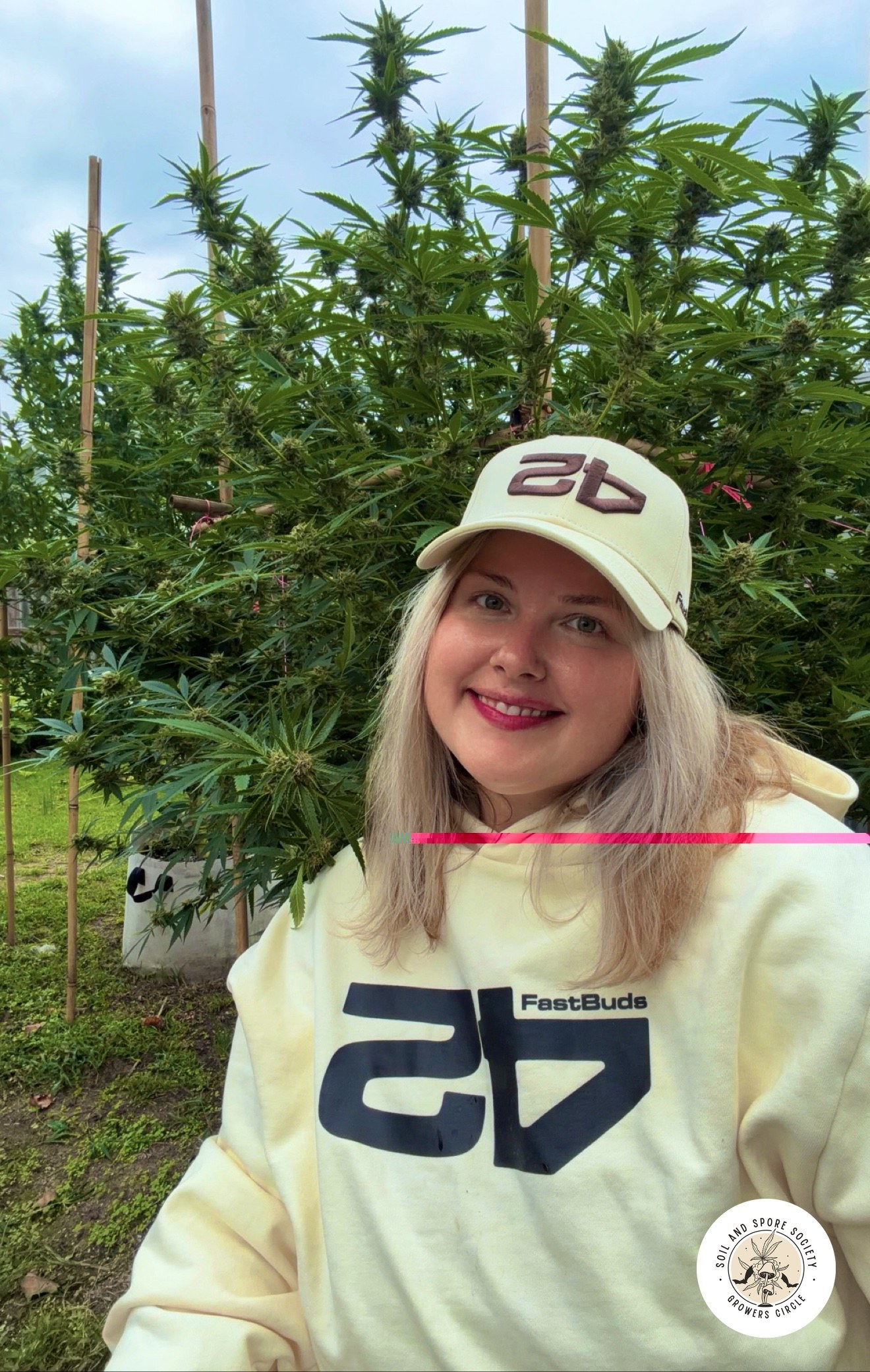 Marina smiling in front of tall outdoor cannabis plants